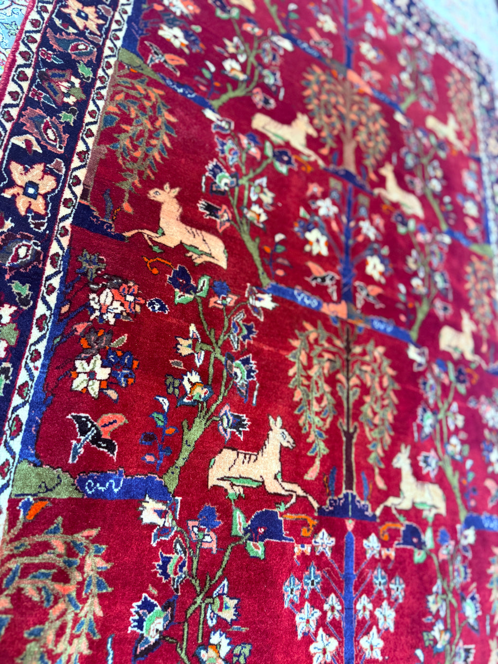 Close-up of a colorful rug with intricate patterns and animals on a red background