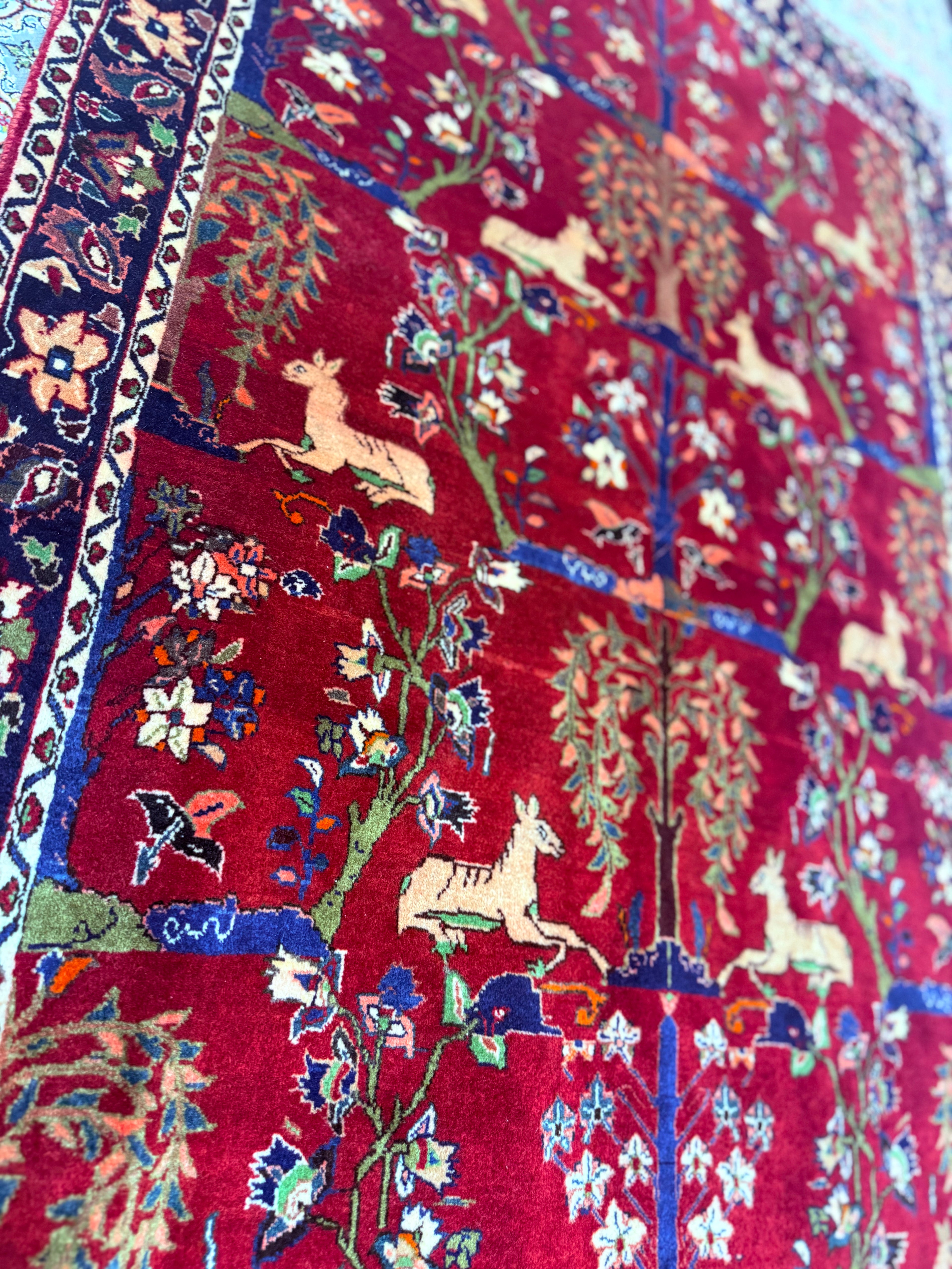 Close-up of a colorful rug with intricate patterns and animals on a red background
