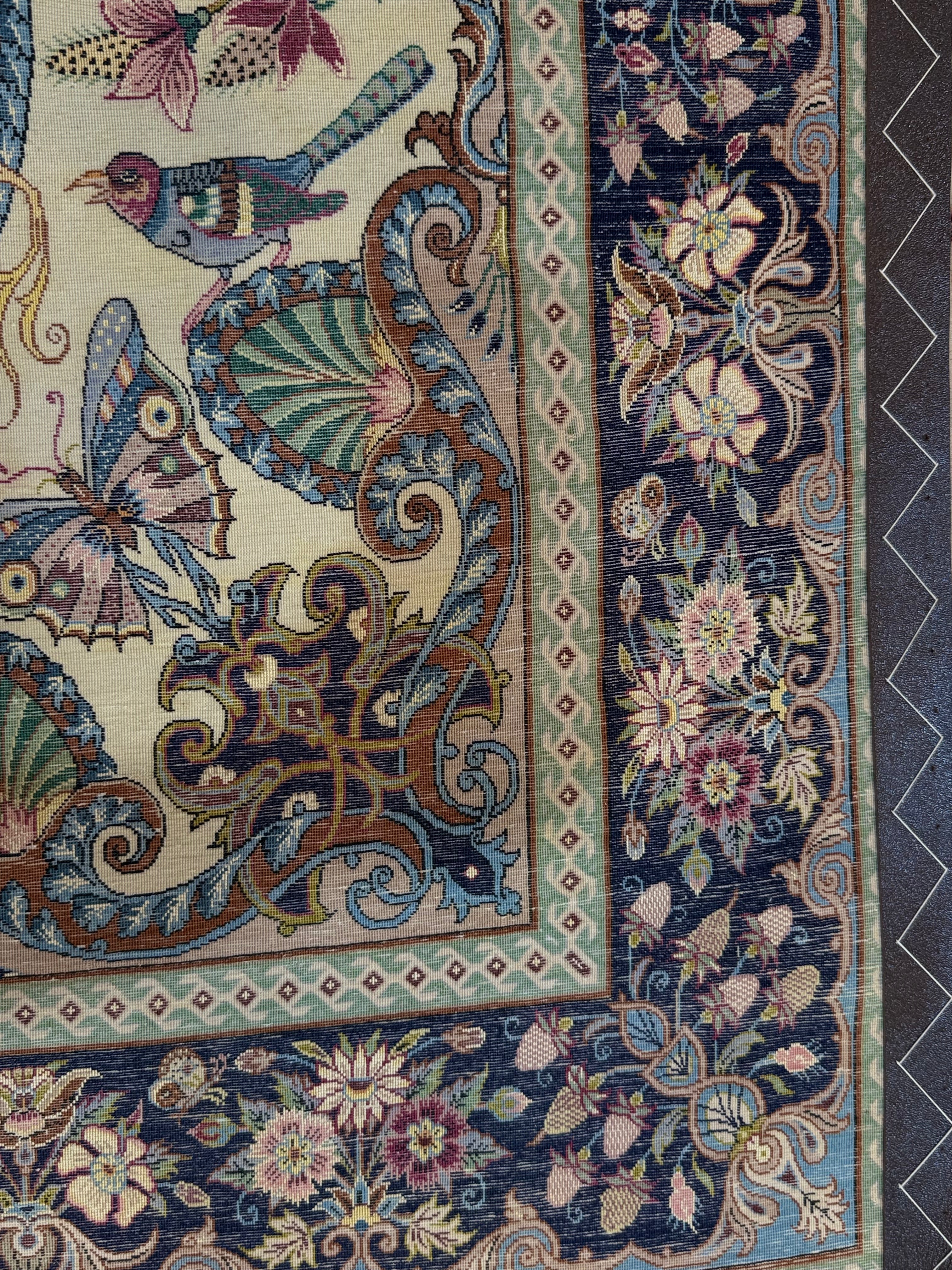 Decorative rug with intricate patterns including birds, butterflies, and flowers.