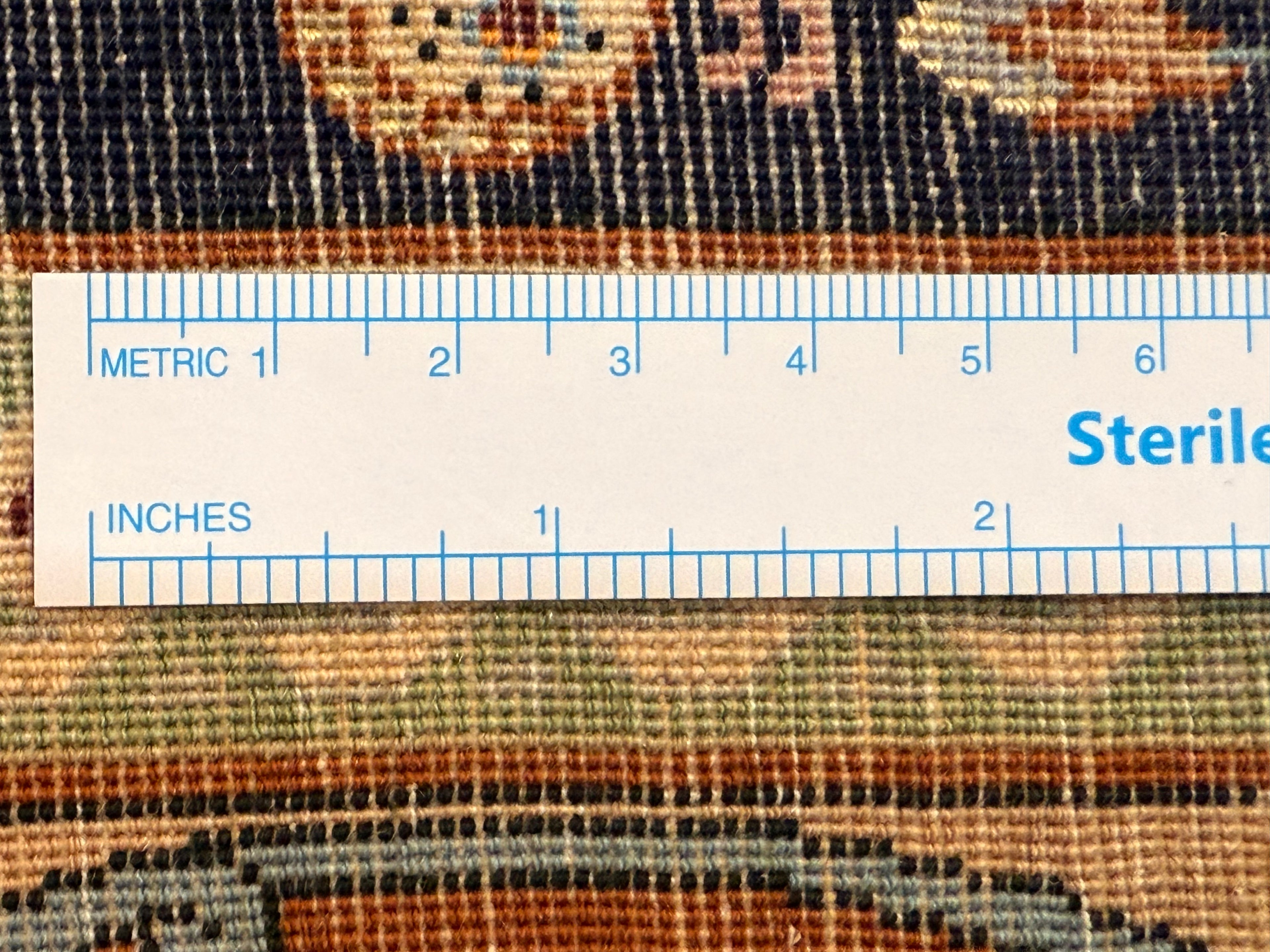 Close-up of a textured fabric with a ruler overlay for measurement, featuring the word 'Sterile'.