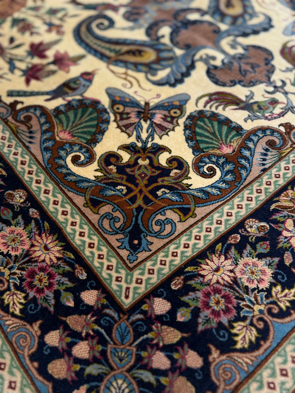 Close-up of a intricately designed rug with floral and butterfly patterns.