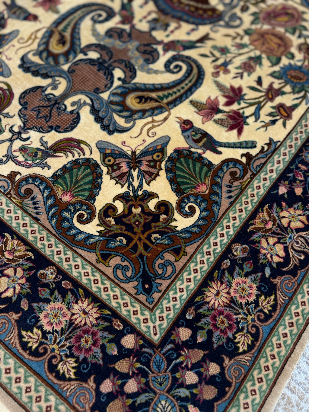 Close-up of a intricately designed rug with floral and butterfly patterns.