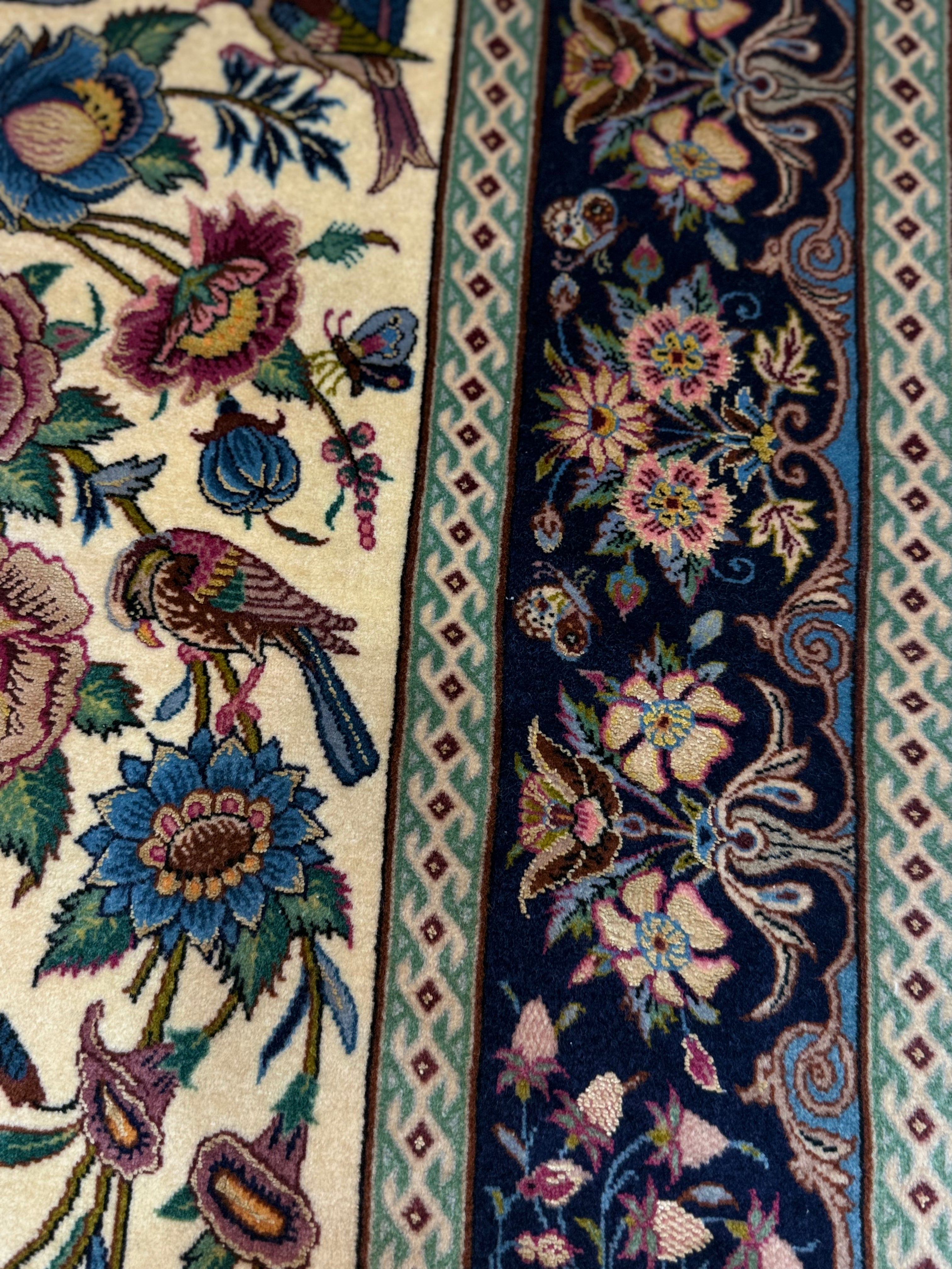 Close-up of a detailed floral and bird pattern on a rug.