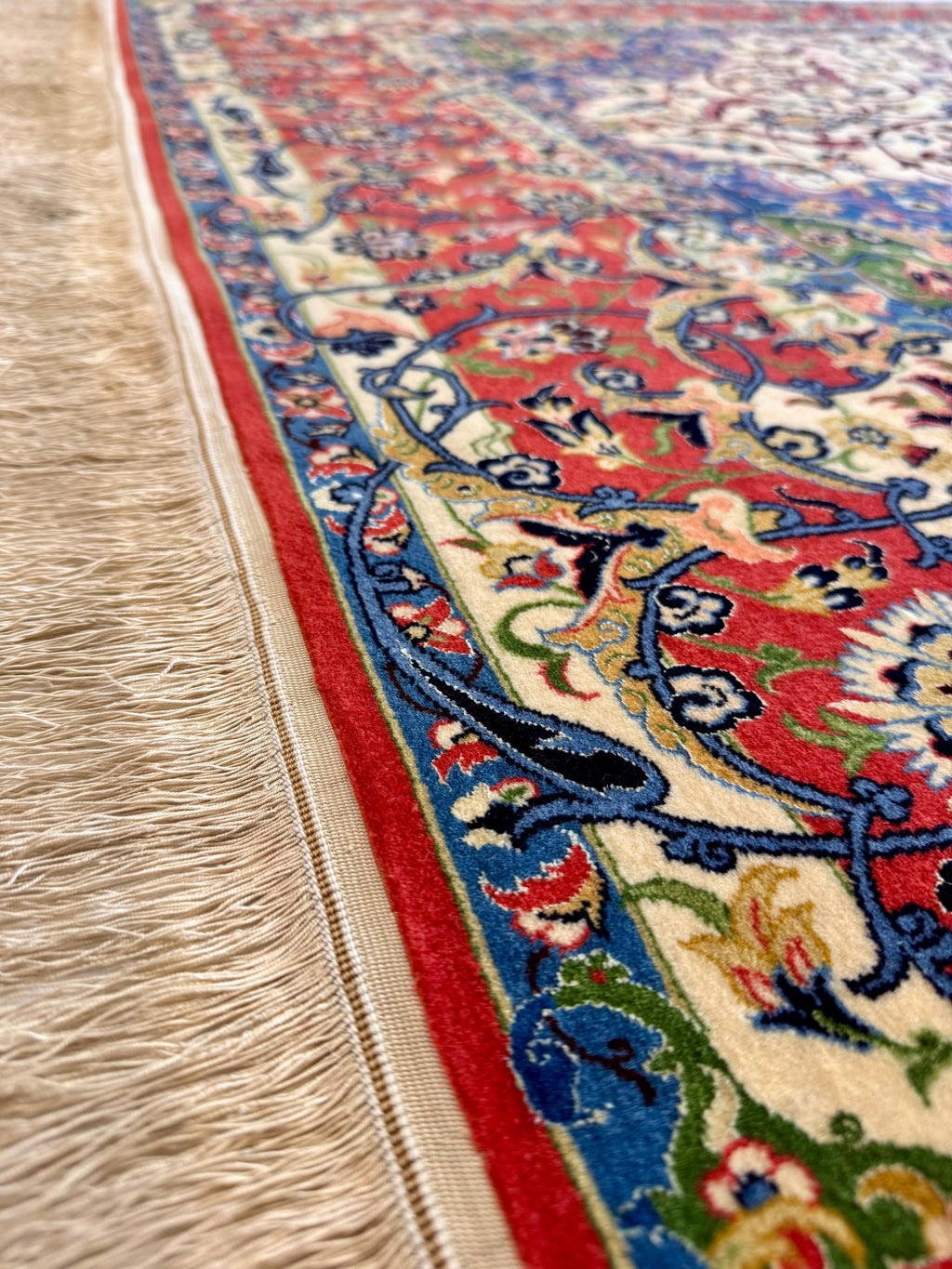 Close-up of a colorful patterned rug with fringed edge on a wooden floor.