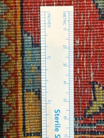 Textile with a colorful pattern and a ruler for measurement on a red background