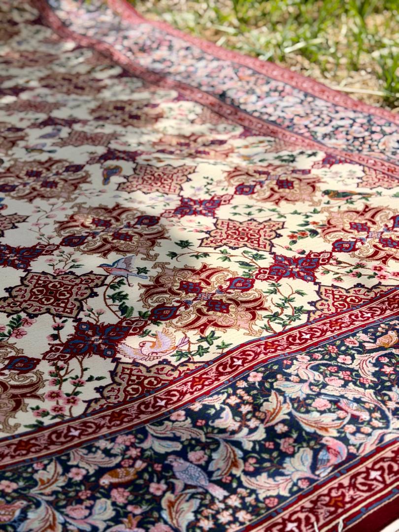 Close-up of a patterned rug with intricate designs on grass.