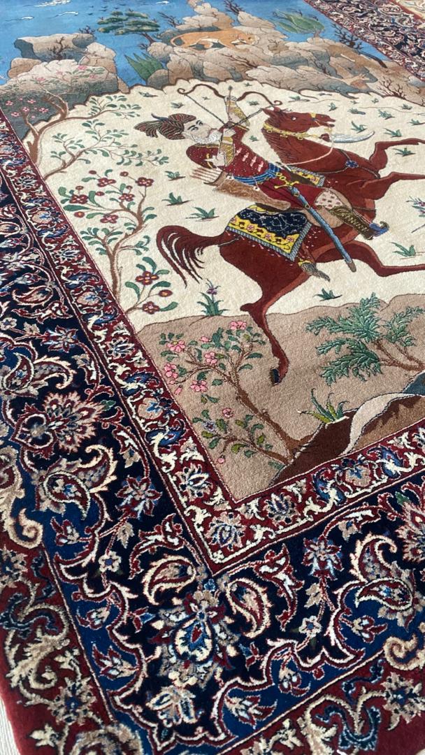 Close-up of an intricately designed rug with a warrior on horseback pattern.